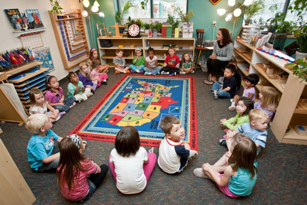 SBS Rm 3 Classroom Map Circle Students learning about geography with Montessori continent maps and flags.